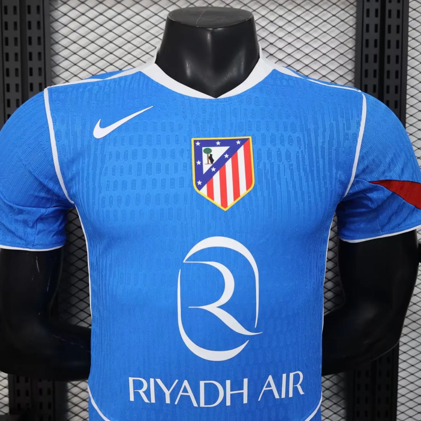 2025/26 Atlético Madrid Away Player Version Jersey - Sky Blue Body All-Over Subtle Diamond Tonal Texture White V-Neck Collar White Trim Red Diagonal Slash Left Sleeve Cuff Accent - White Swoosh - Atlético Madrid Official Shield Crest - Riyadh Air - Men's