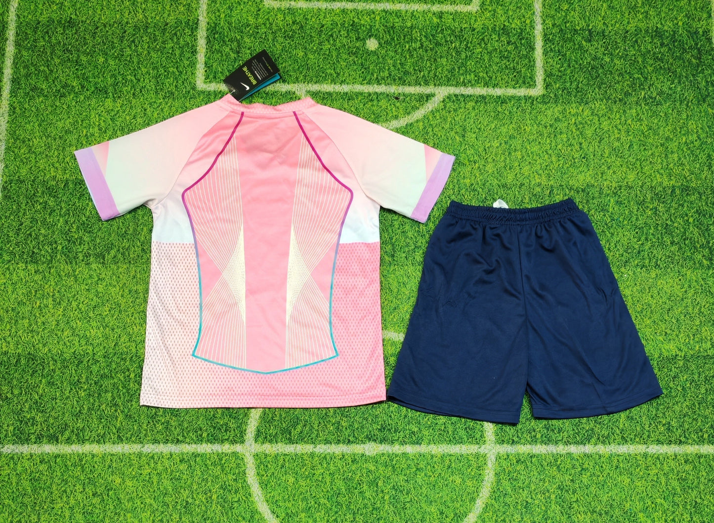 2025/26 FC Barcelona Kids Third Kit Set - Pink Jersey Navy Blue Shorts  - Pink Body White Lavender Sleeve Panels Teal V-Neck Geometric Radial Line Texture - White Nike Swoosh - FCB Pink Monochrome Crest - Spotify Navy Blue Sponsor